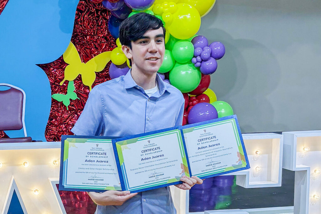 a student showcases three certificates indicating scholarship awards