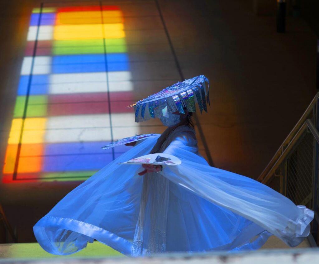 dancer with costume dances against lighted background