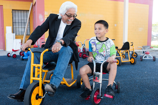 a grandfather rides small bikes with his grandson while both smile