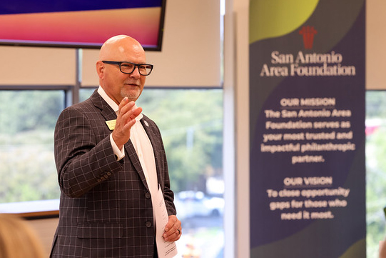 David Simmons speaks at the front of a training room with the Area Foundation mission in the background