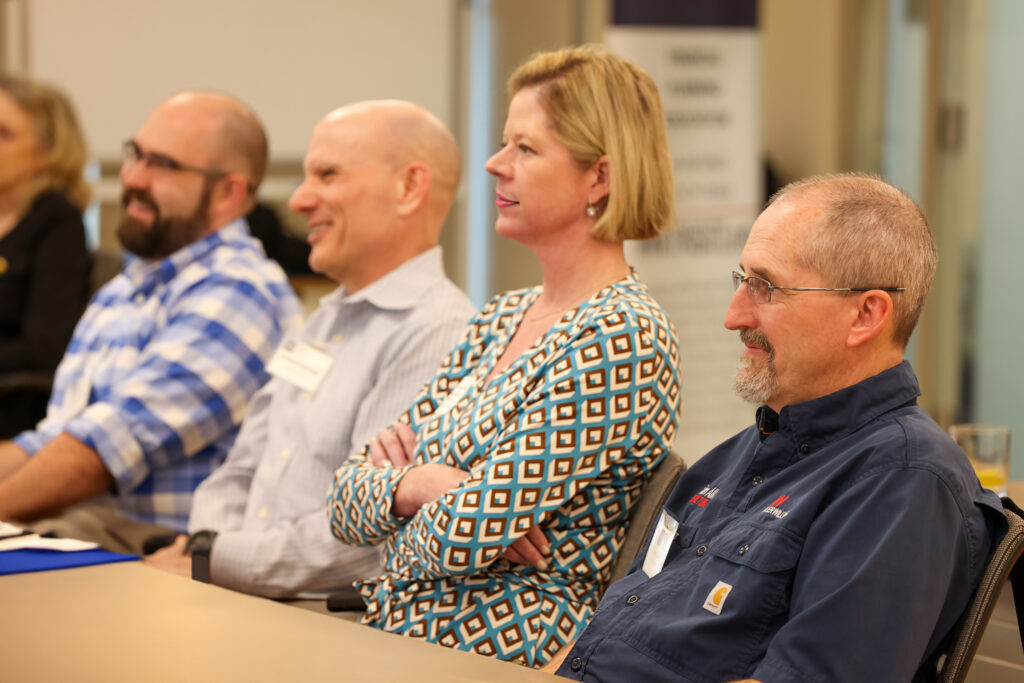 4 professional advisors sit at a table listening to a speaker