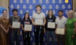 five students hold scholarship certificates in front of a Somerset ISD step and repeat